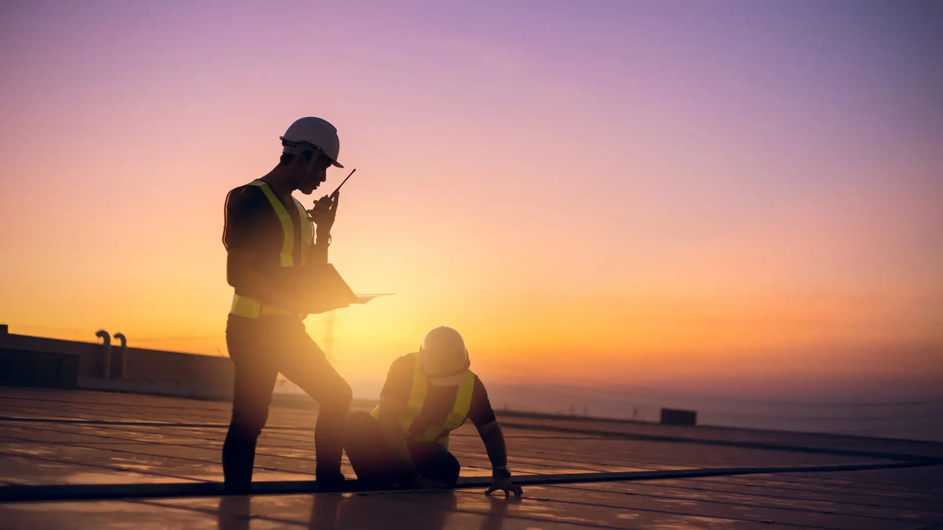 Two technicians service yearly preventive maintenance solar cells on roof factory under morning sunlight.